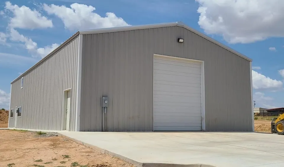 Completed Homerun Fabrication metal shop with tan siding and rollup door in Amarillo, TX