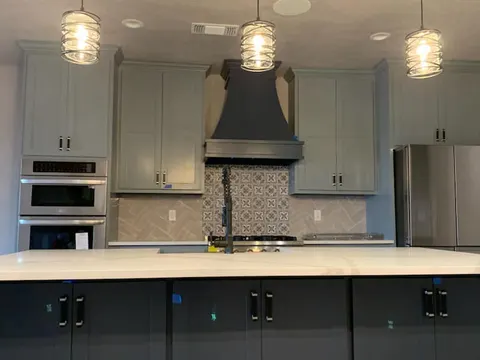 Custom kitchen build-out with gray cabinets and pendant lights inside a Homerun Fabrication barndominium