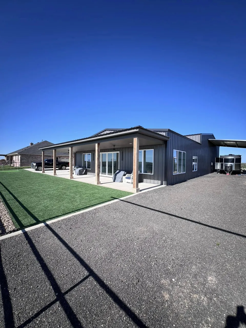 Dark charcoal barndominium with covered front porch built by Homerun Fabrication