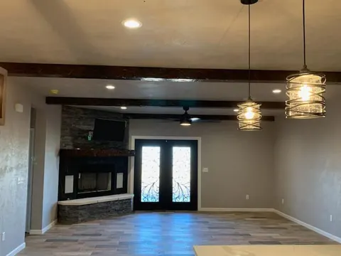 Finished barndominium living room with stone fireplace and wood beam ceiling built by Homerun Fabrication